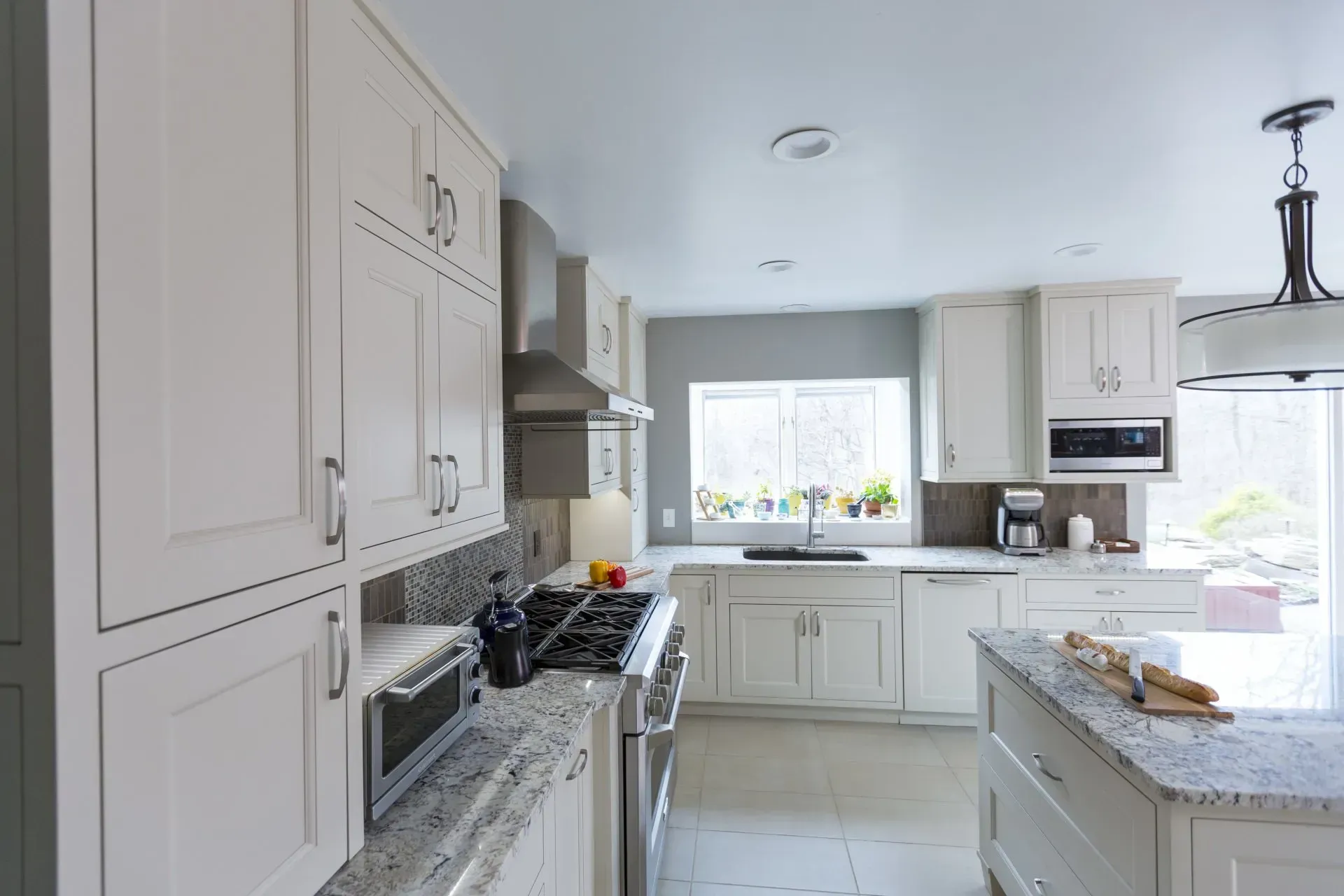 A kitchen with white cabinets , granite counter tops , stainless steel appliances and a large island.