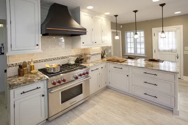 A kitchen with white cabinets , stainless steel appliances and granite counter tops.