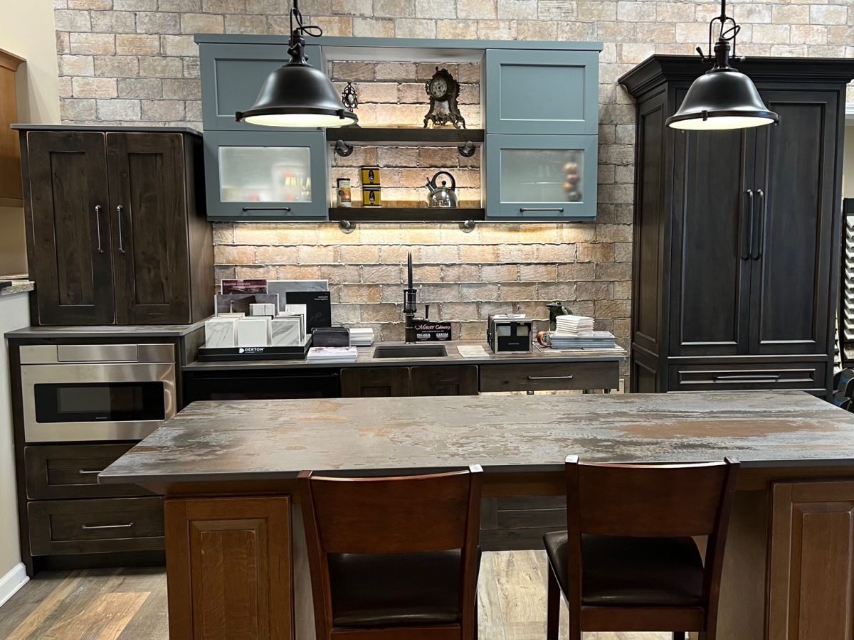 A kitchen with a large island and chairs and a brick wall.