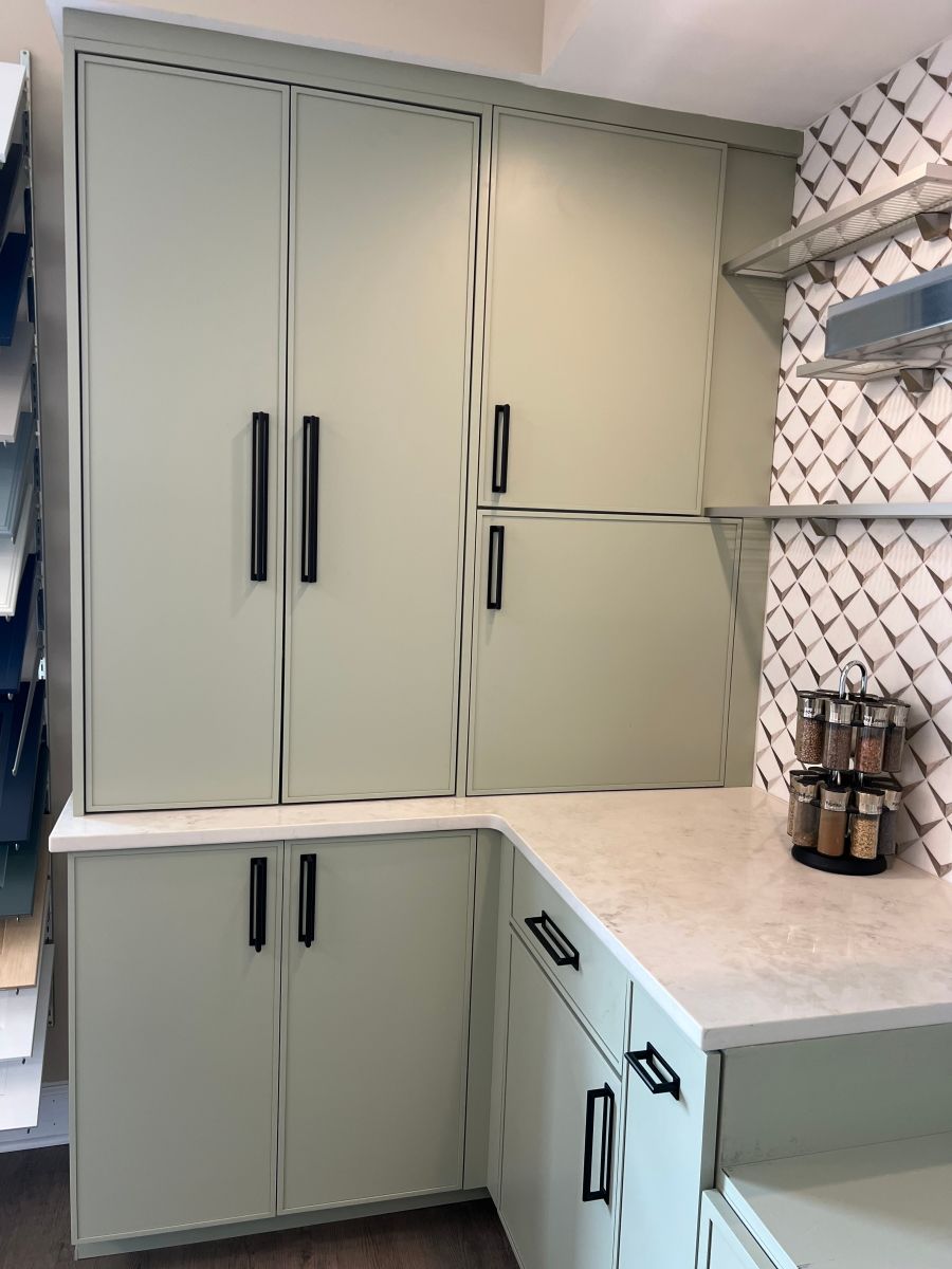 A kitchen with green cabinets and a marble counter top.