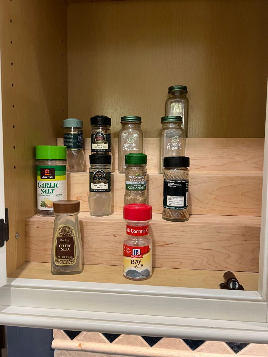 A cabinet filled with bottles of spices on a wooden shelf.