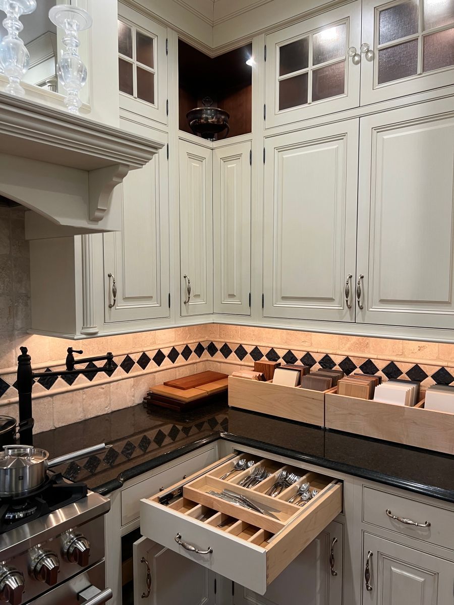 A kitchen with white cabinets and a drawer filled with silverware