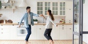 A man and a woman are dancing in a kitchen.