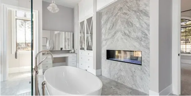 A bathroom with a tub and a fireplace in the wall.