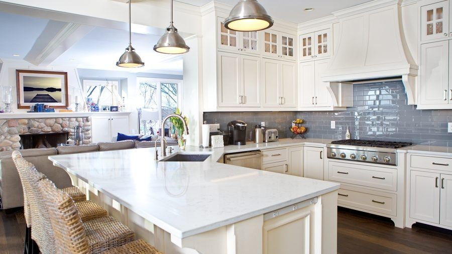 A kitchen with white cabinets , granite counter tops , stainless steel appliances and a large island.