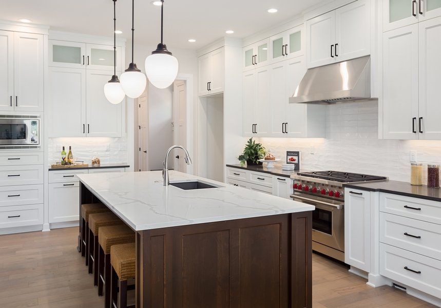 A kitchen with white cabinets and stainless steel appliances and a large island.