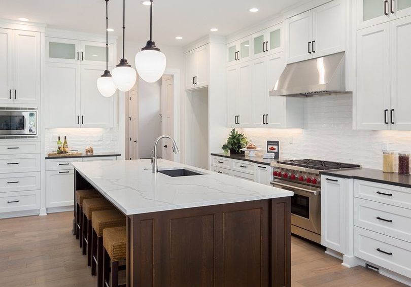 A kitchen with white cabinets and stainless steel appliances and a large island.