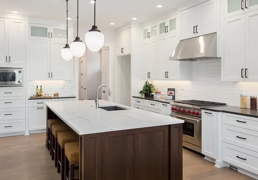 A kitchen with white cabinets , stainless steel appliances , and a large island.