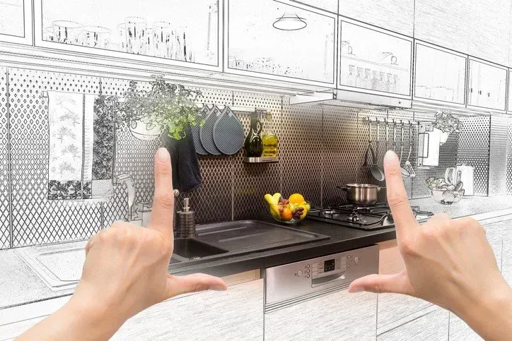 A person is framing a drawing of a kitchen with their hands.
