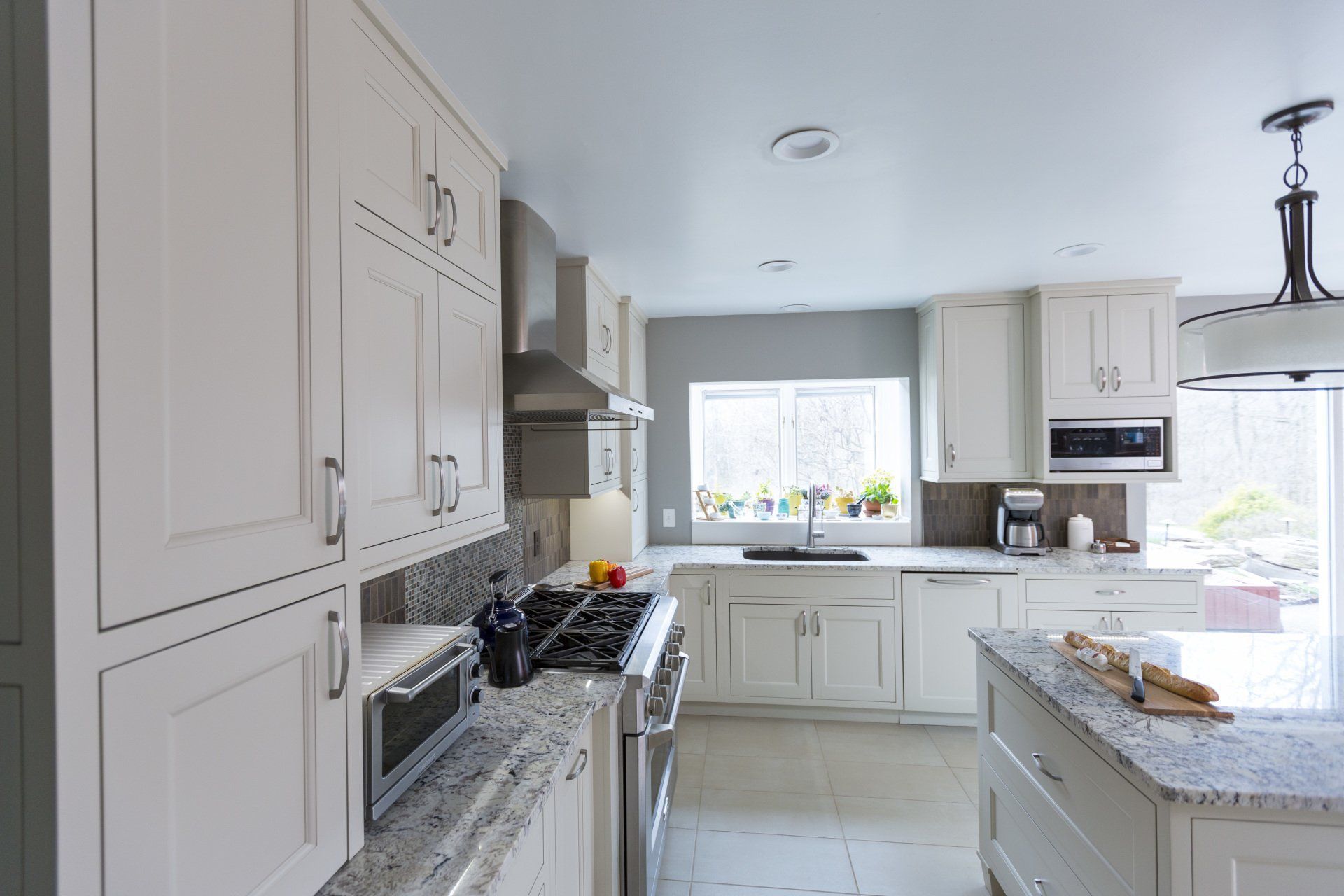 A kitchen with white cabinets , granite counter tops , stainless steel appliances and a large island.