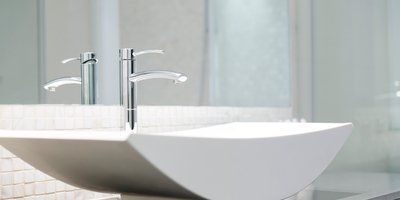 A bathroom sink with two faucets and a mirror.