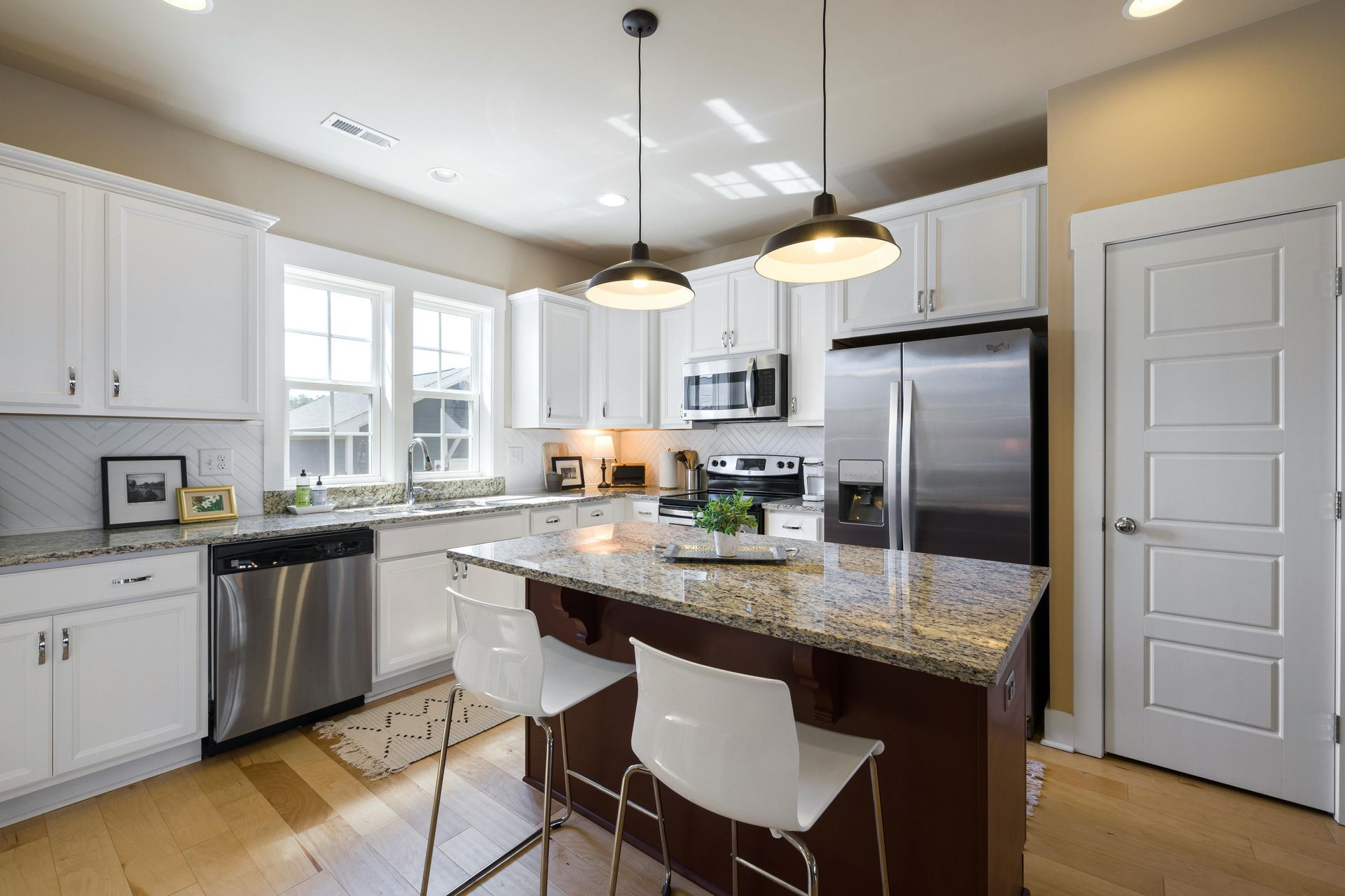 A kitchen with white cabinets , granite counter tops , stainless steel appliances and a large island.