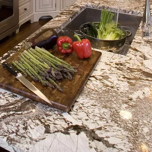 A kitchen with white cabinets and a large island with a marble counter top.