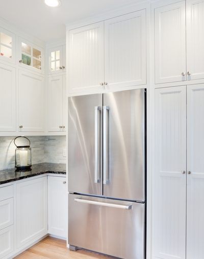 A kitchen with white cabinets and a stainless steel refrigerator