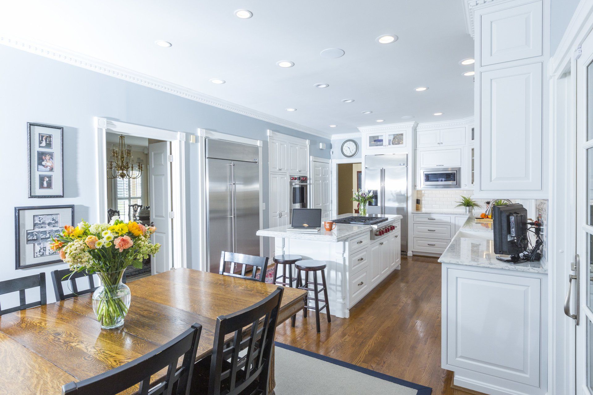 A kitchen with a table and chairs and a vase of flowers on the table.