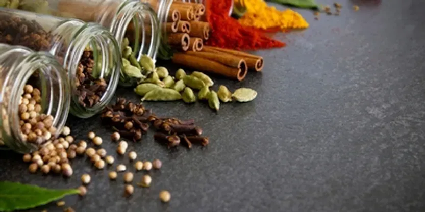 A variety of spices are spilling out of jars on a table.