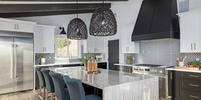 A kitchen with black and white cabinets , stainless steel appliances , and a large island.