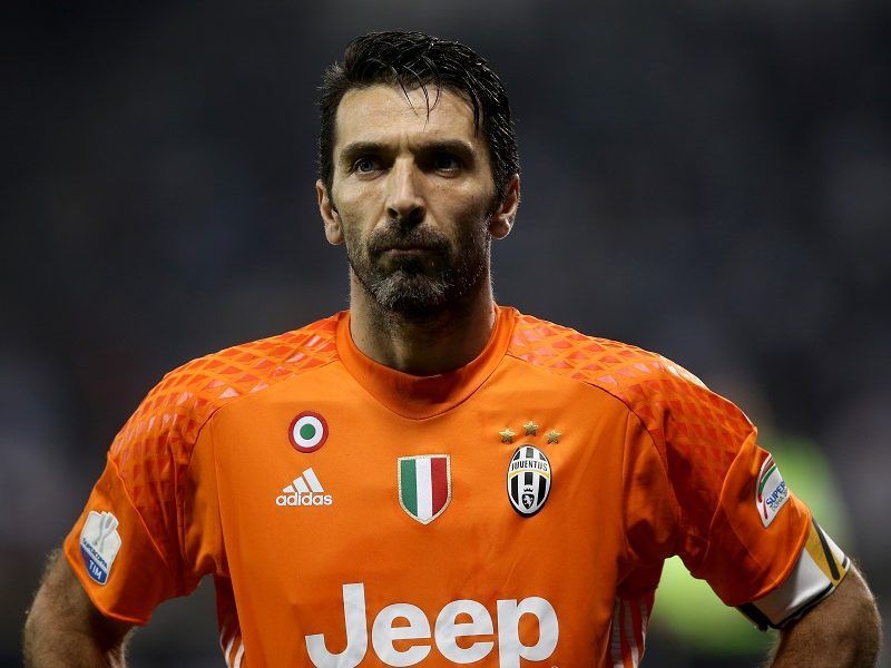 Gianluigi Buffon, portero de la Juventus, con camiseta naranja, de pie en un campo.