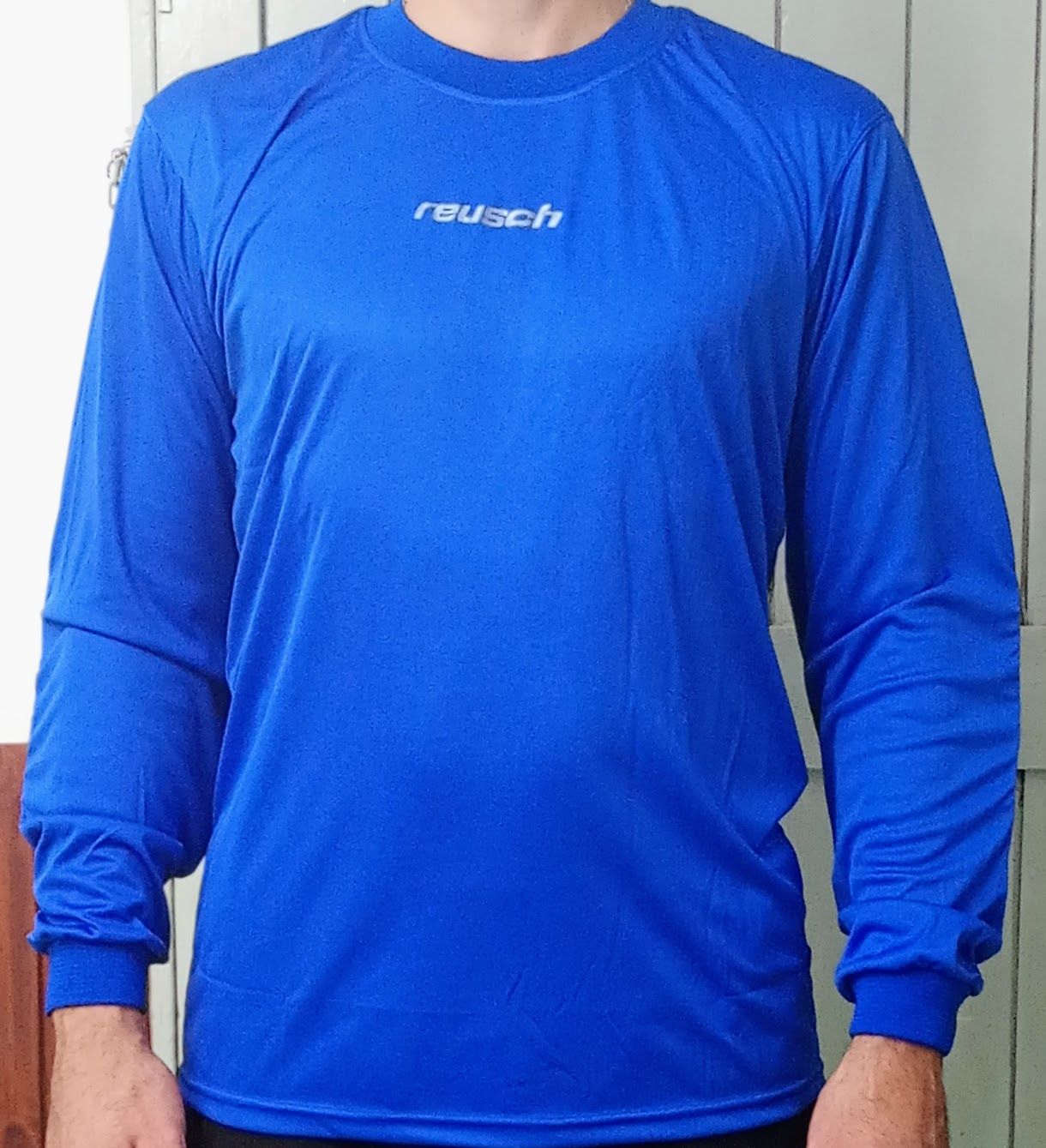 Persona que lleva una camisa azul de manga larga con el logotipo "Reusch" en el pecho.