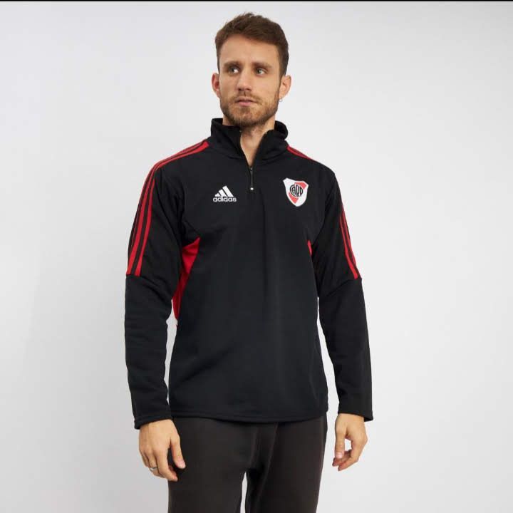 Hombre vistiendo una camiseta de entrenamiento Adidas negra con rayas rojas y el logo de River Plate.