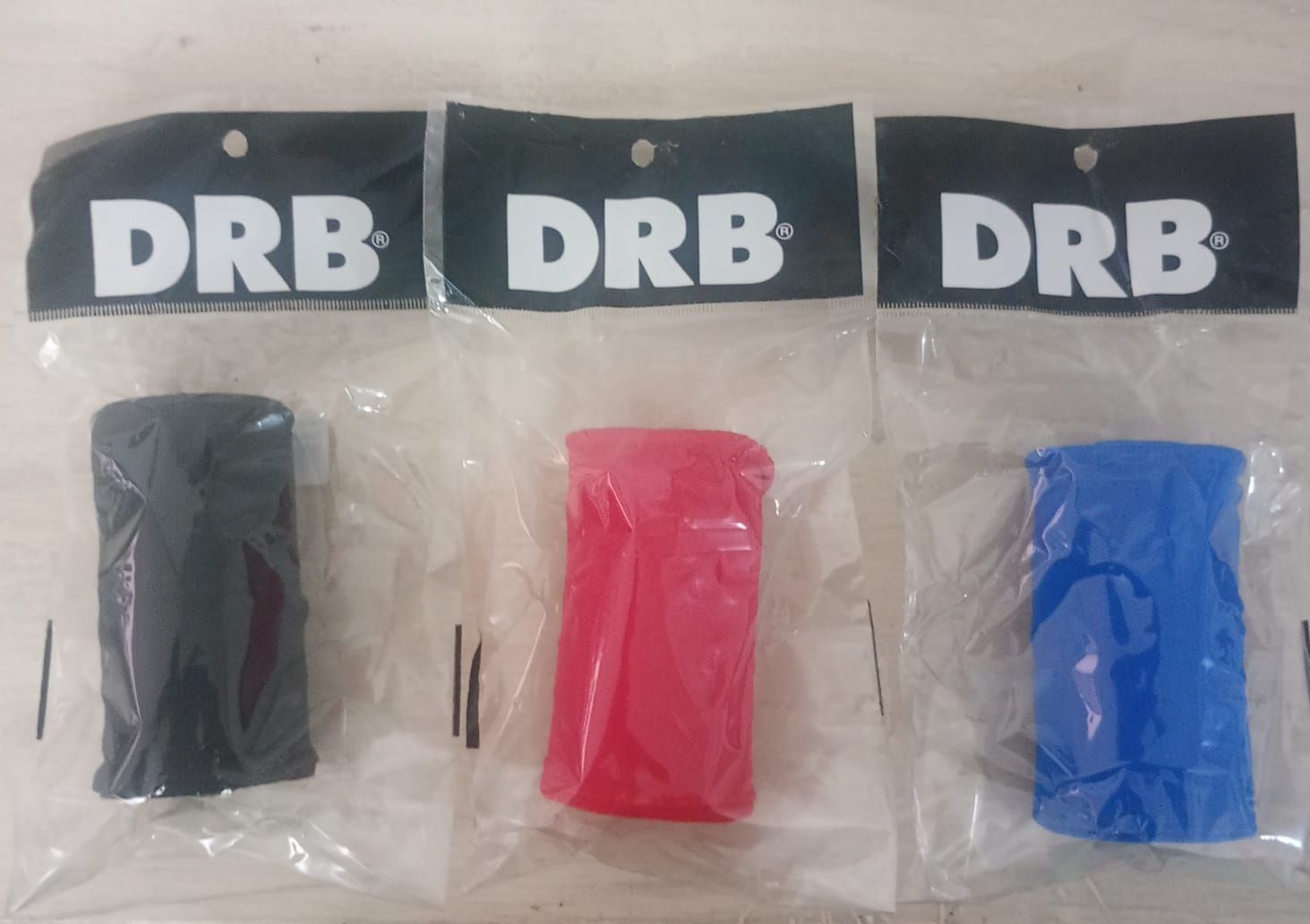 Tres cintas de agarre de la marca DRB en color negro, rojo y azul, cada una en una bolsa de plástico transparente.