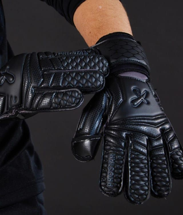 Guantes de portero de fútbol negros en las manos de una persona.
