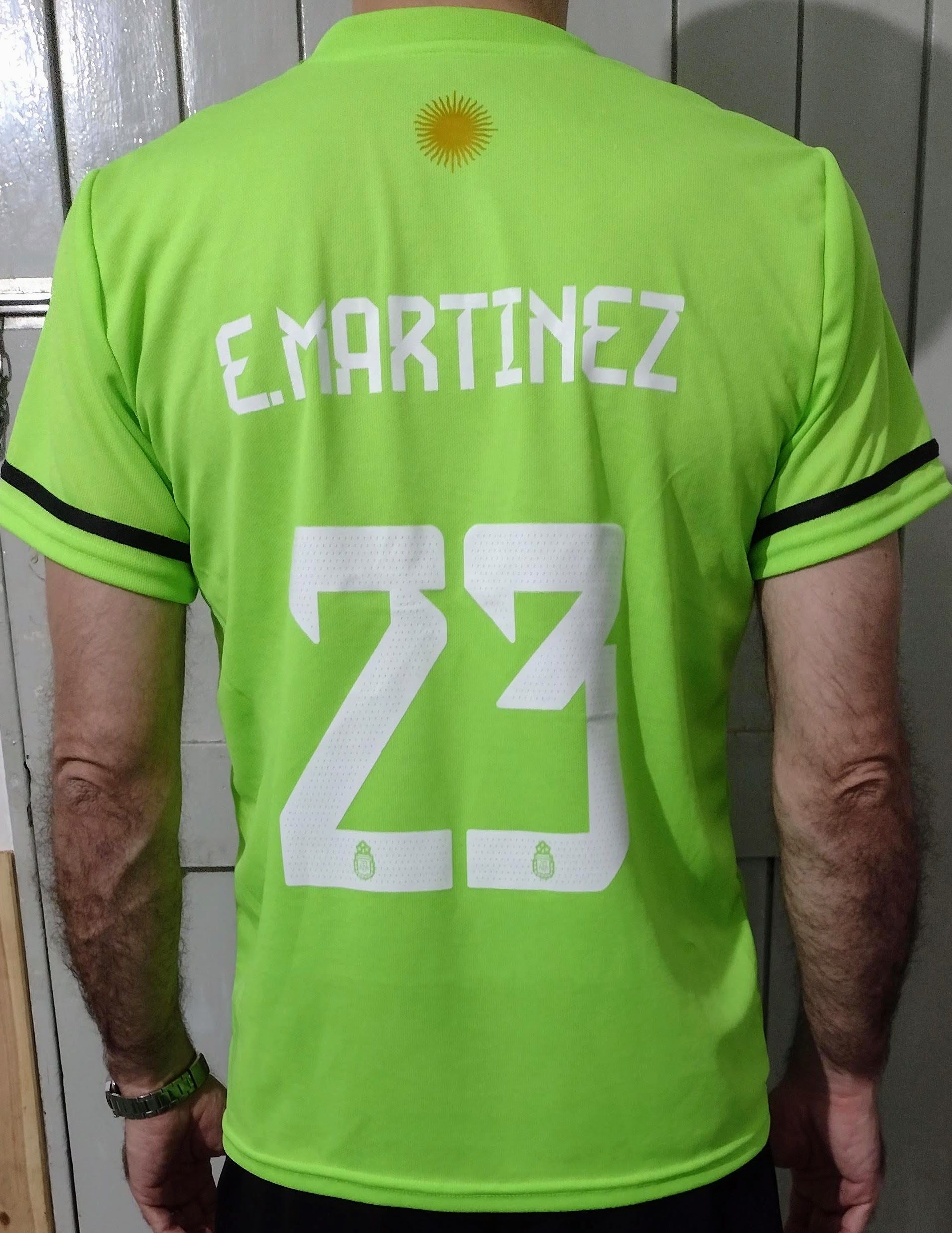 Persona que viste una camiseta de fútbol de Argentina verde brillante con el número 23.
