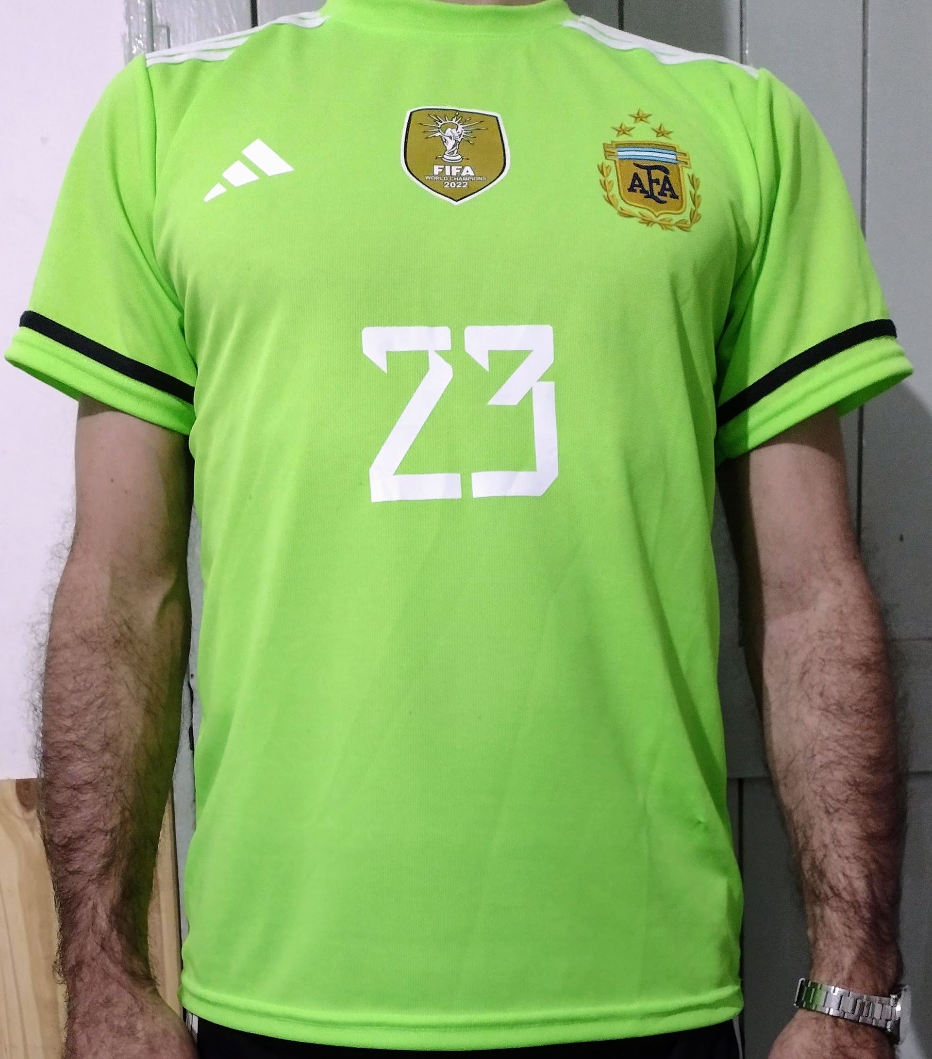 Persona que viste una camiseta de fútbol de Argentina verde brillante con el número 23.