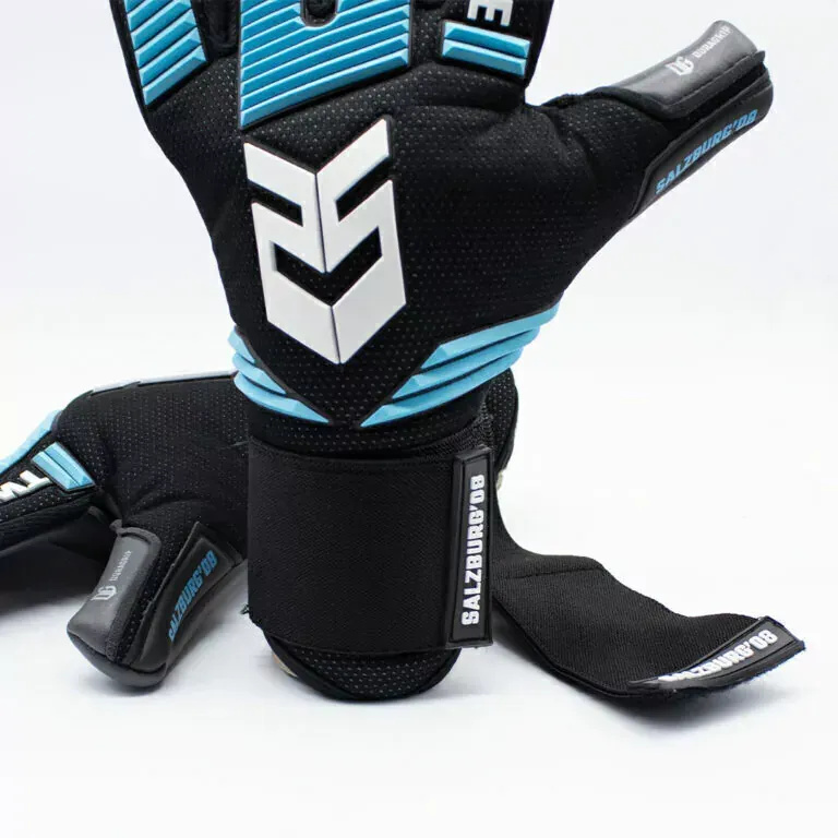 Dos guantes de portero, uno negro y otro azul claro, mostrados desde el frente y el reverso sobre un fondo blanco liso.