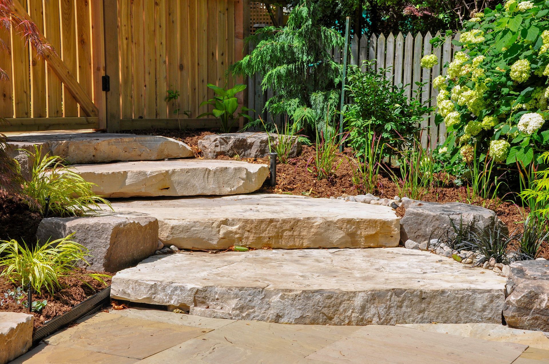 A Stone Staircase Leading up To a Wooden Fence in A Garden - Kinston, NC - Garden Gator Landscape & Design