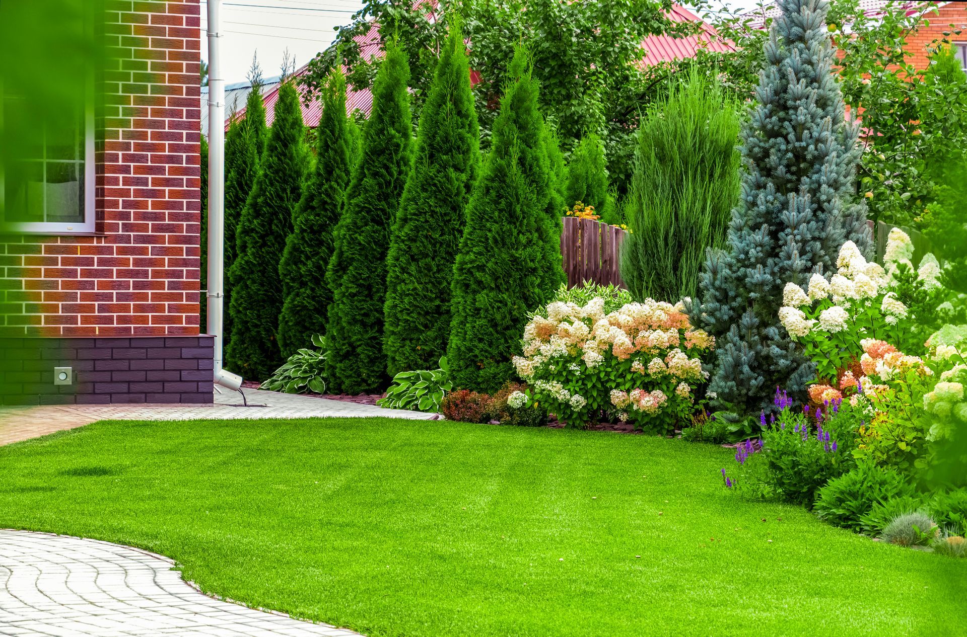 A Lush Green Yard with Trees and Flowers in Front of A Brick House - Kinston, NC - Garden Gator Landscape & Design