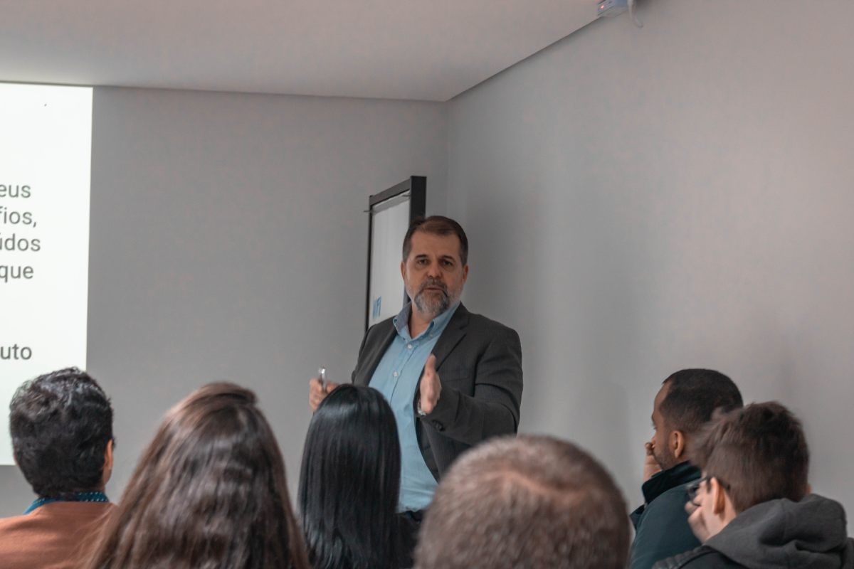 Um homem está fazendo uma apresentação para um grupo de pessoas em uma sala.