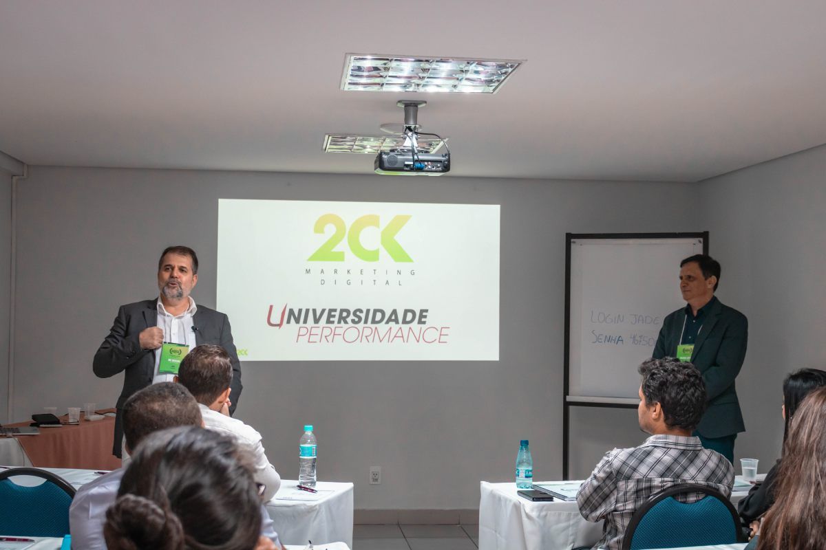 Dois homens estão fazendo uma apresentação para um grupo de pessoas em uma sala.