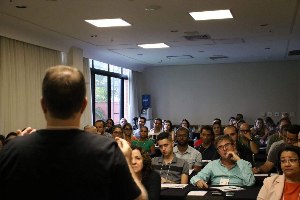Um homem está fazendo uma apresentação para um grande grupo de pessoas em uma sala de conferências.