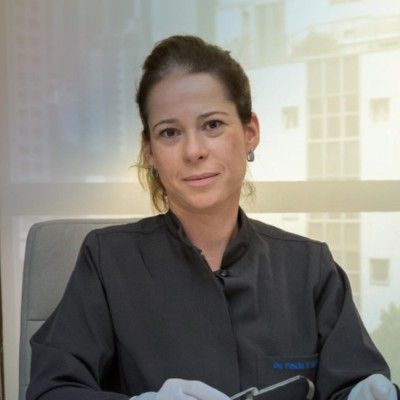 Uma mulher de jaleco está sentada em uma cadeira