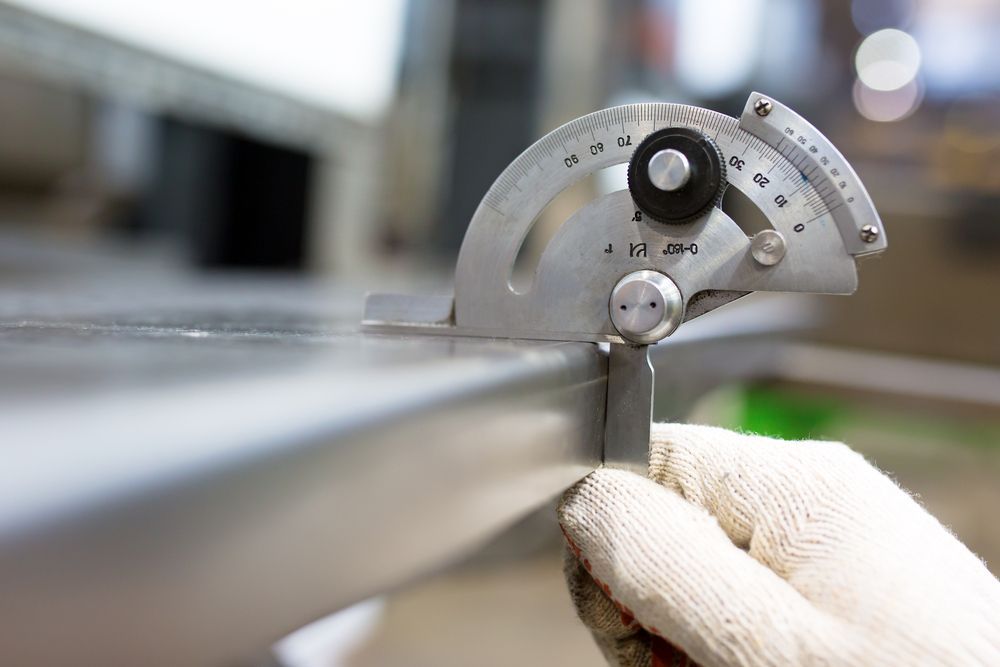 Gloved Hand Uses a Protractor to Measure the Angle of a Metal Piece — Bryants Laser Works in Logan, QLD