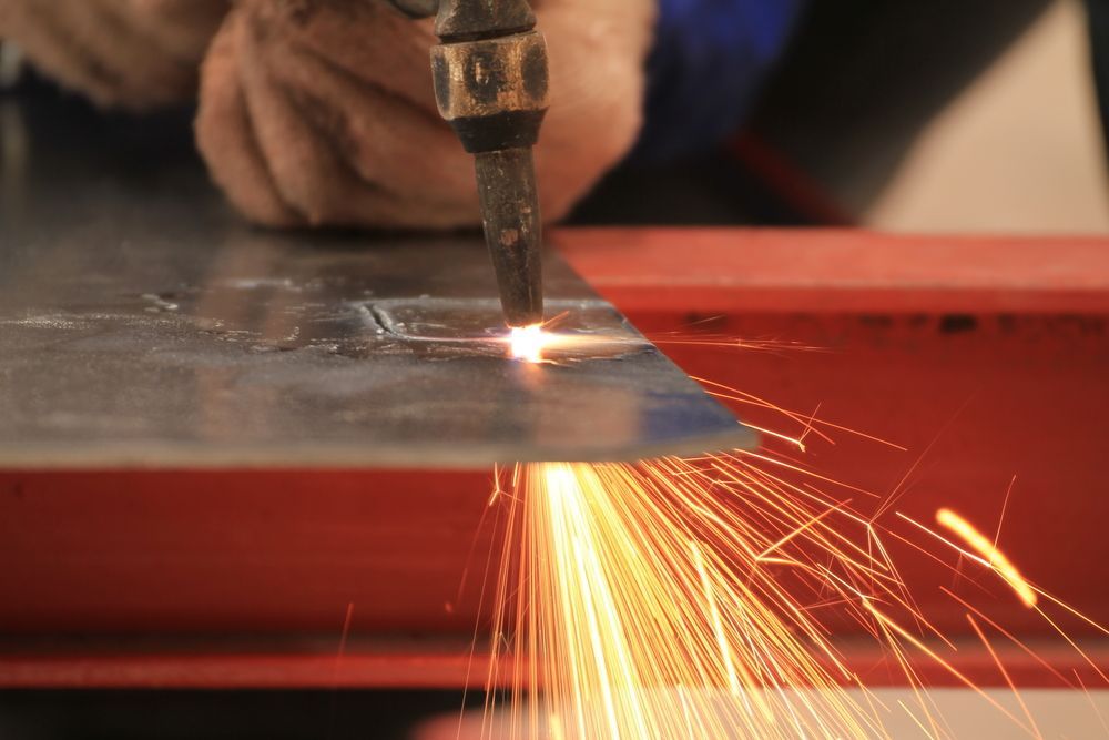 Person Cutting Metal Sheet With a Torch, Sparks Flying — Bryants Laser Works in Brisbane, QLD