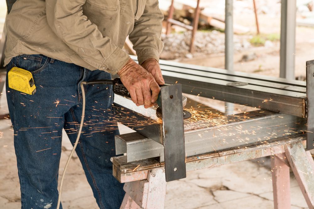 Person Cutting Metal With a Power Tool, Sparks Flying — Bryants Laser Works in Ipswich, QLD