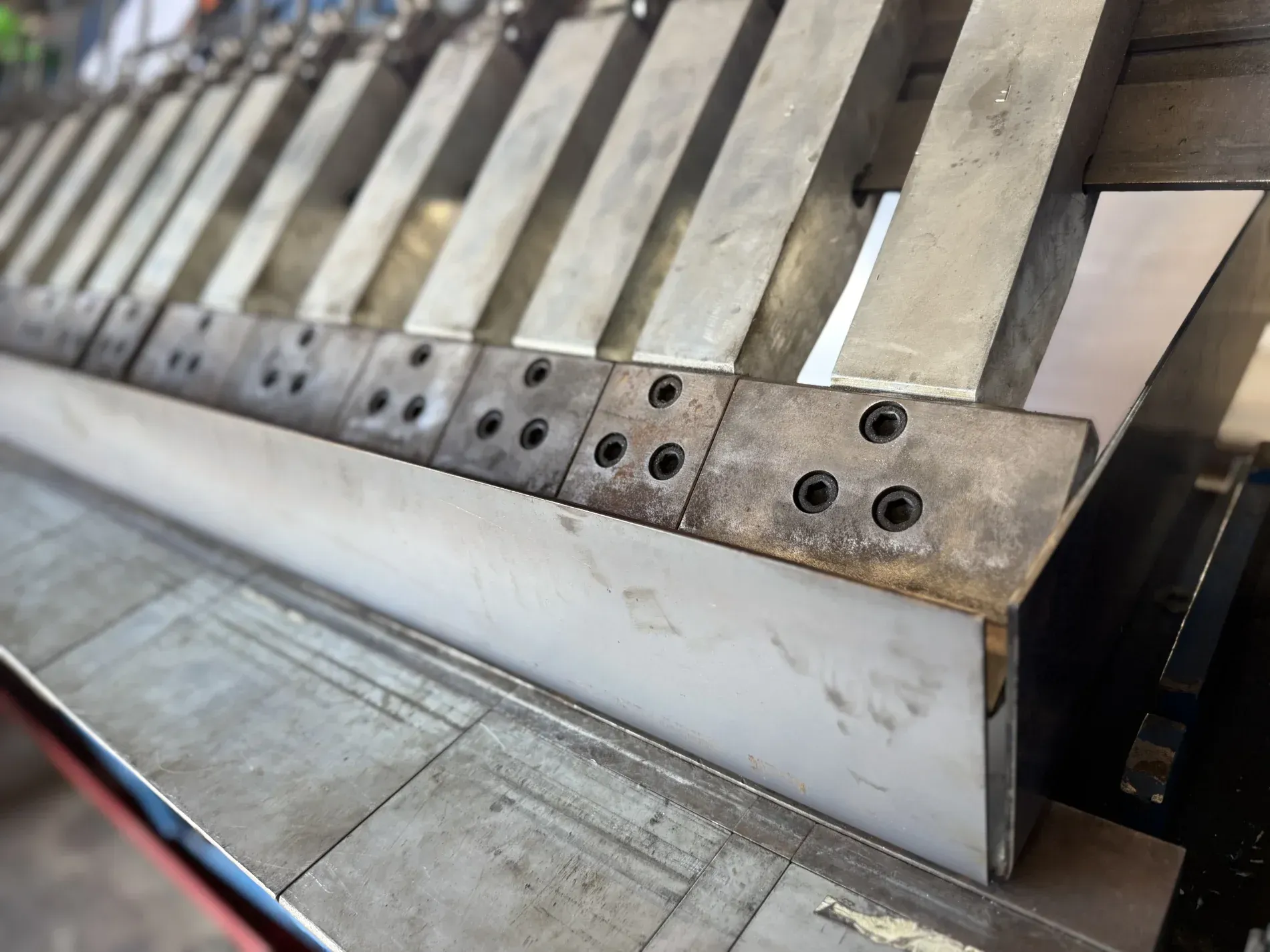 Metal sheet being bent by a machine. Gray metal is in focus, industrial setting — Bryants Laser Works in Logan, QLD