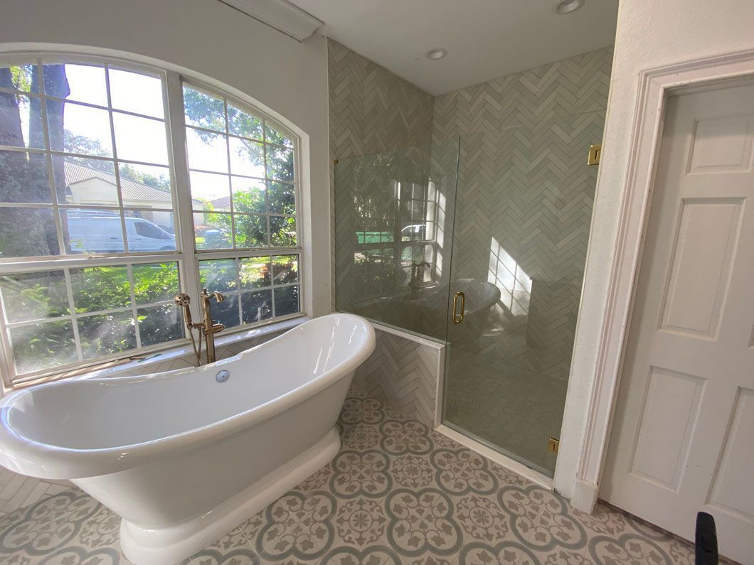 Bathroom with a white clawfoot tub, patterned tile floor, and a glass-enclosed shower.