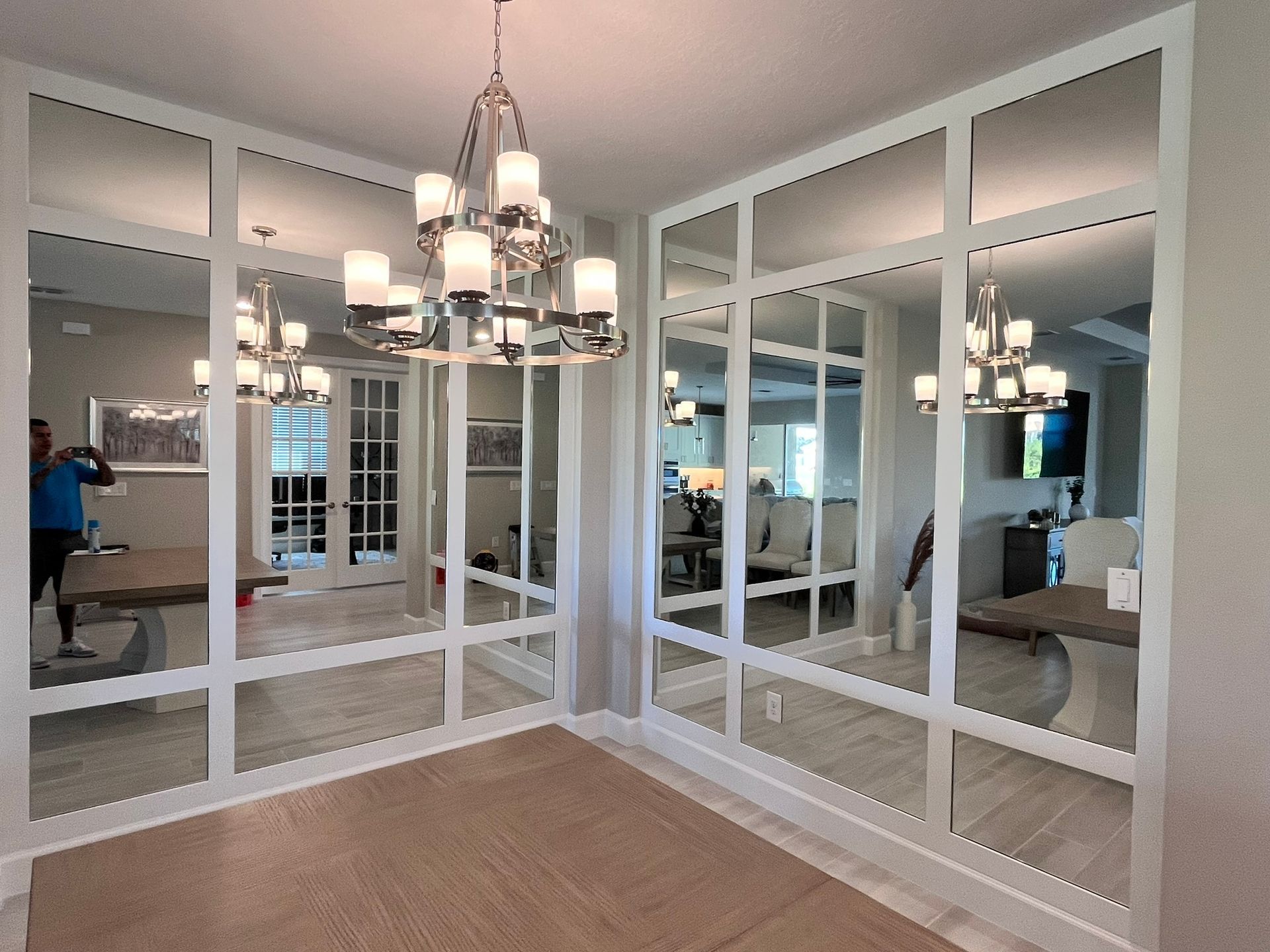 Dining room with mirrored walls, white trim, chandelier, and hardwood floors.