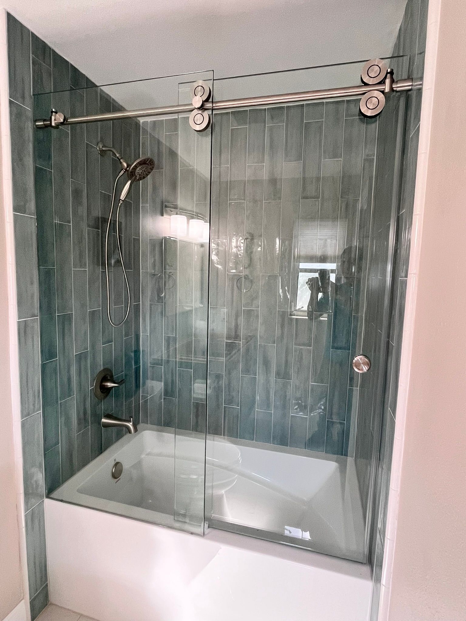Blue tiled shower with a glass sliding door and chrome hardware.