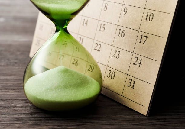 An hourglass and calendar, the hourglass is flowing and the calendar shows the end of the month.