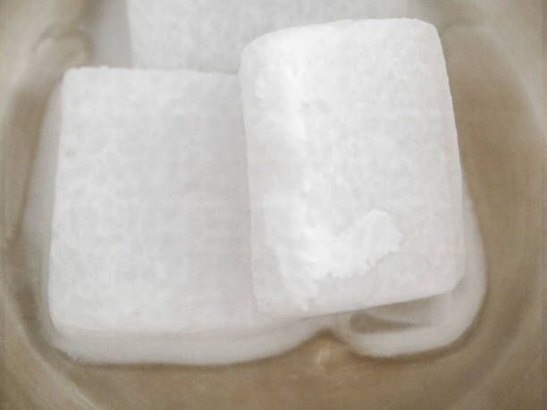 Three white, rectangular dry ice blocks in a container, with visible condensation.