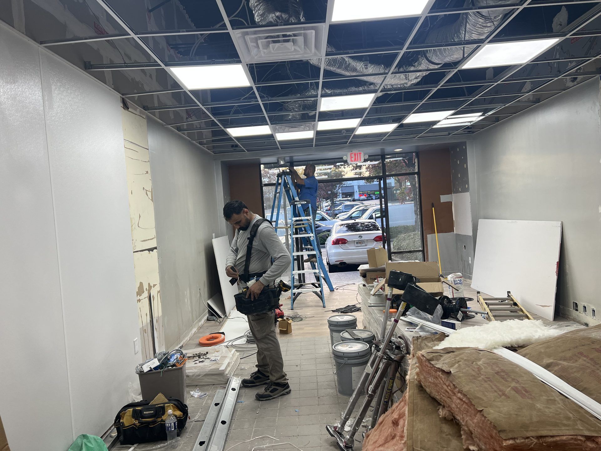 Tenant improvement buildout in progress with licensed trades coordinating ceiling and electrical wor