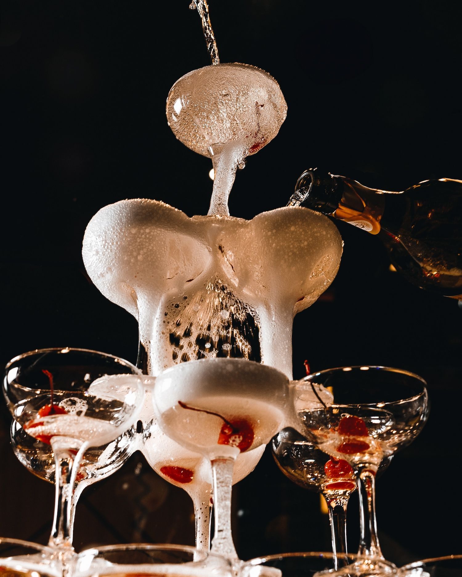 A pyramid of champagne glasses with a cherry on top