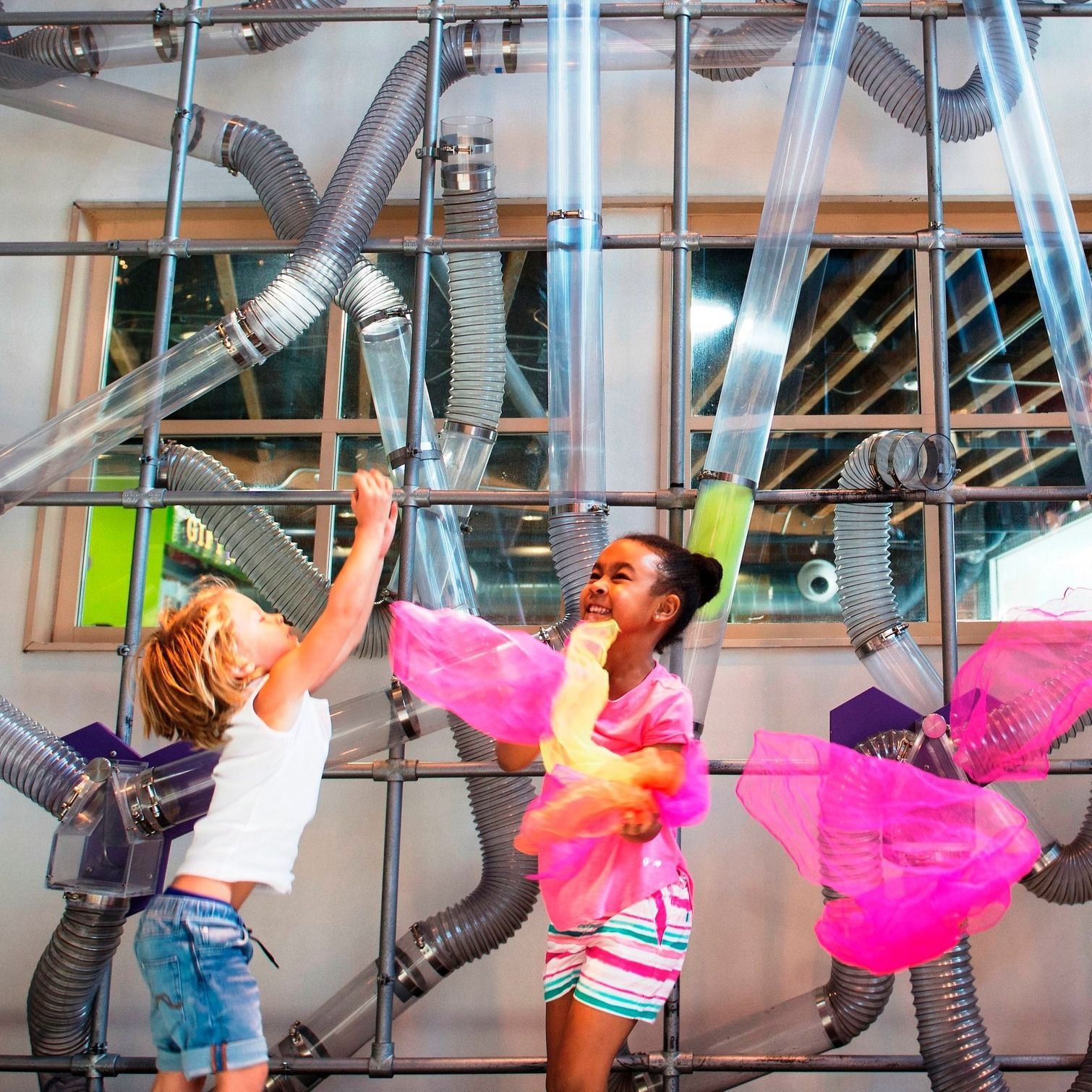 A boy and a girl are playing in a maze of pipes