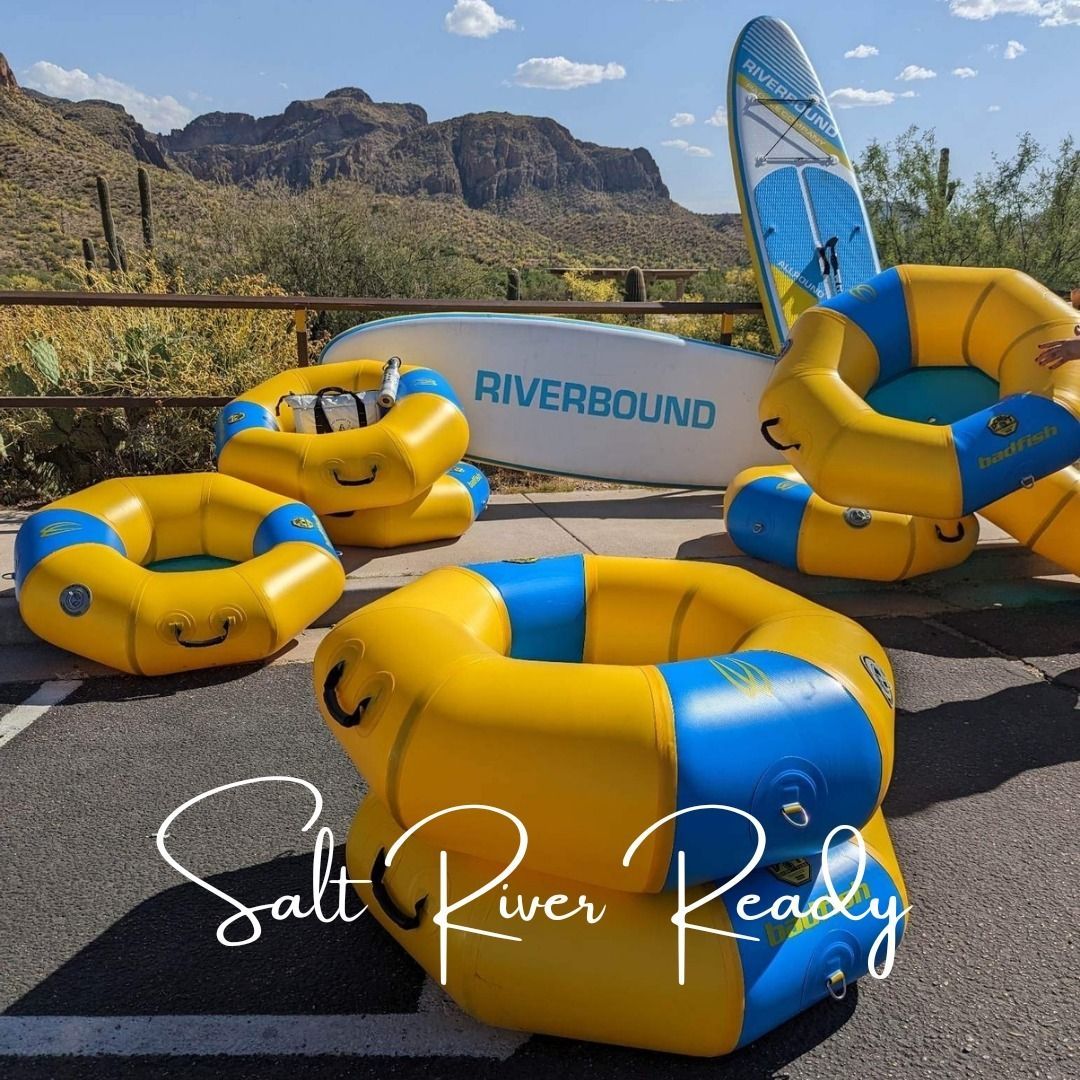 Rafts and a surfboard in front of a sign that says riverbound
