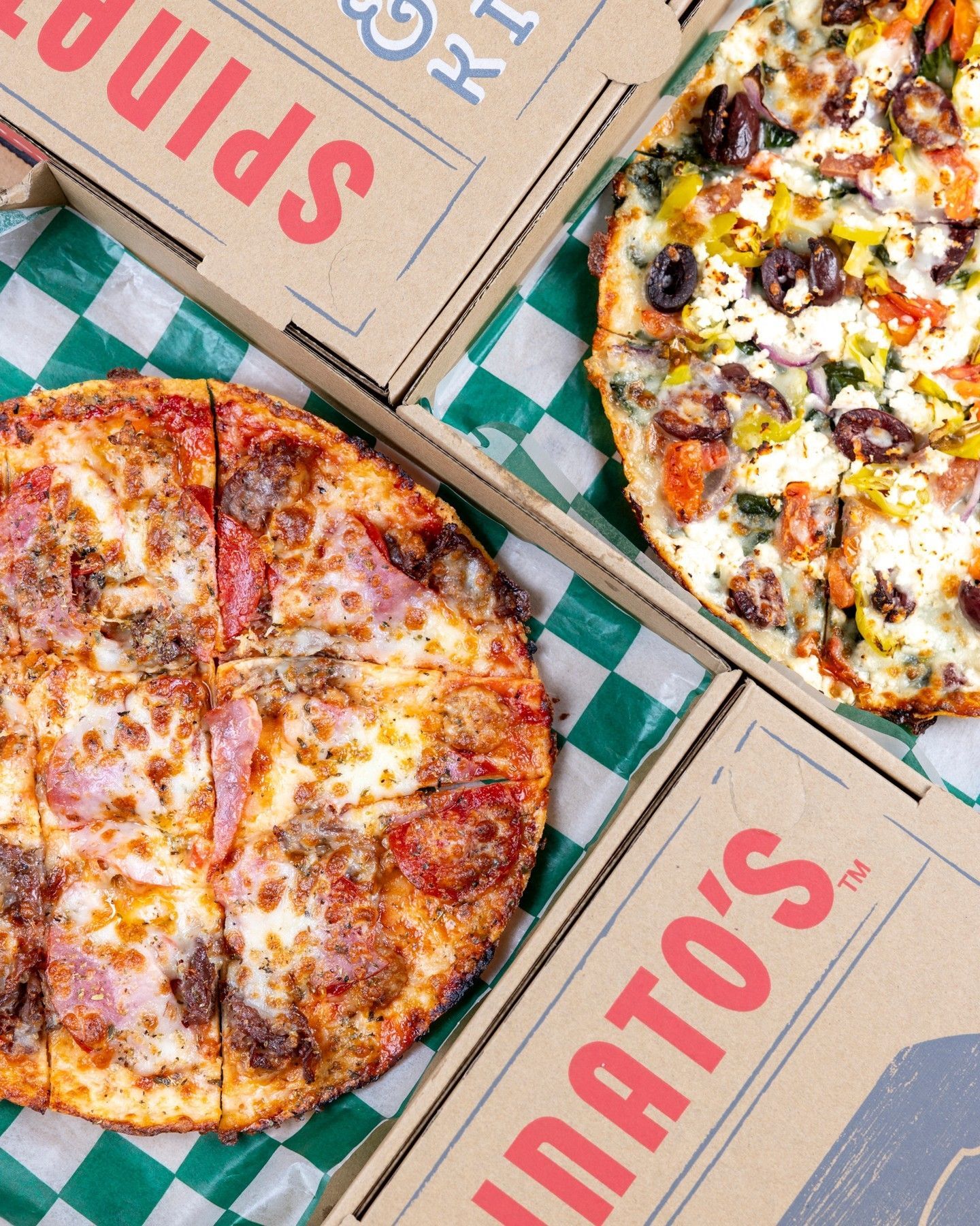 Two pizzas are sitting next to each other on a checkered table cloth.