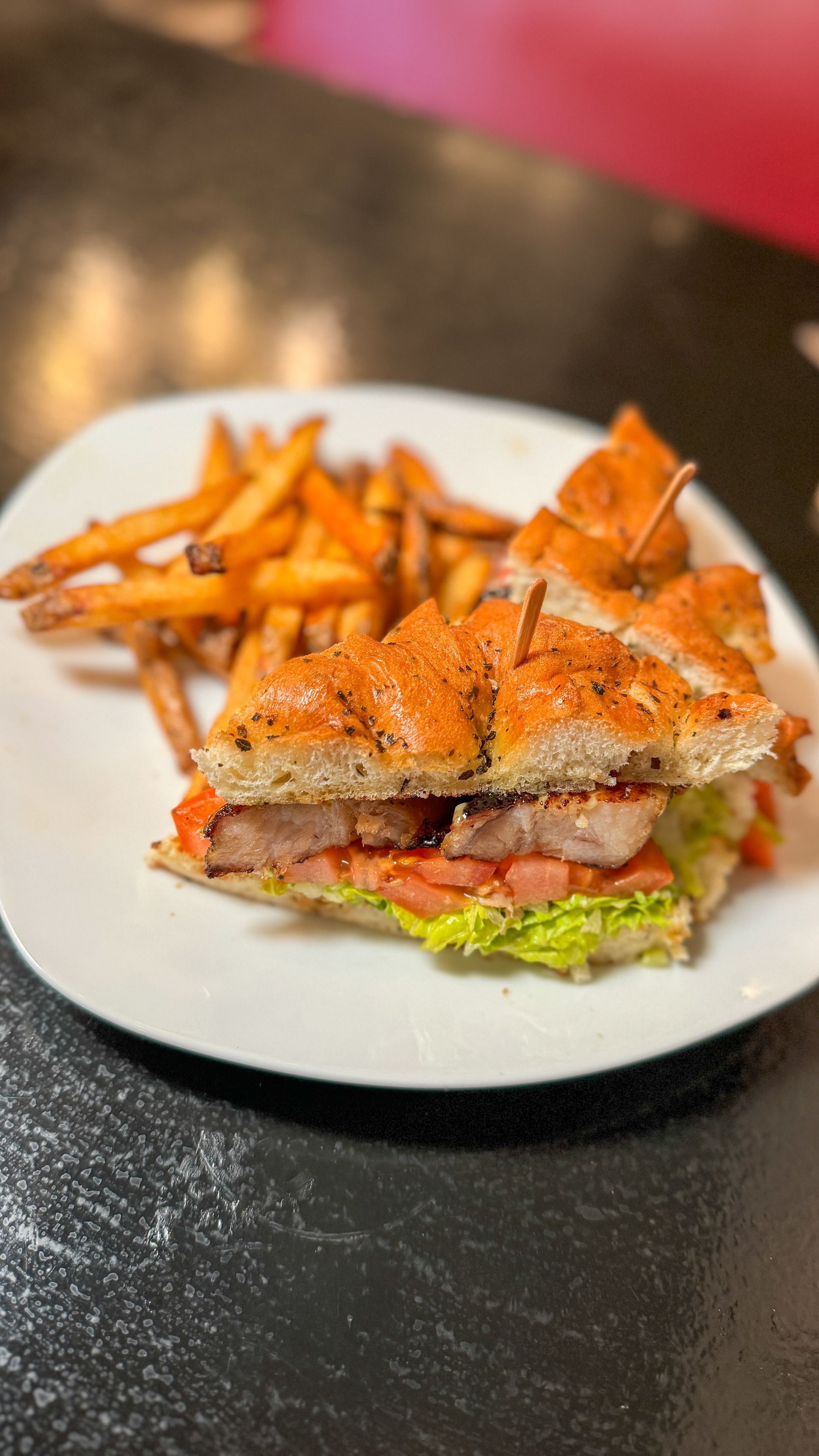 A sandwich and french fries on a white plate on a table.